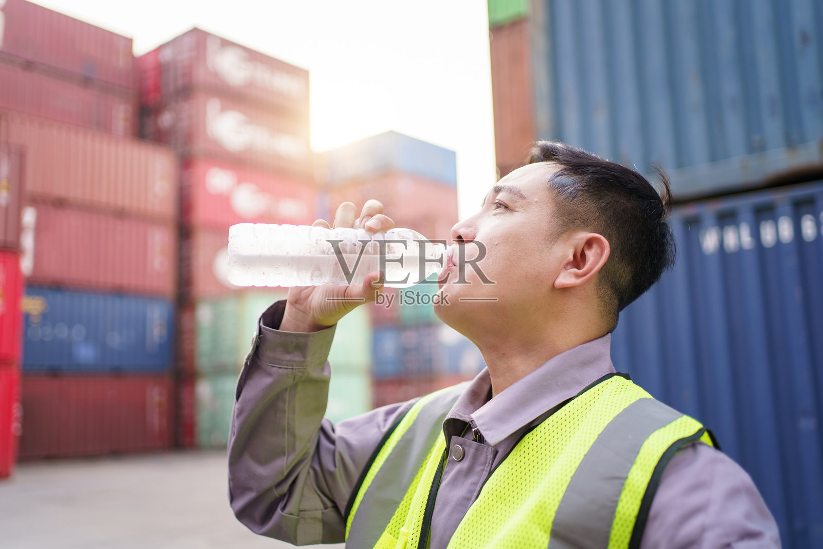 亚洲集装箱场工人在炎热的天气中休息，喝水。照片摄影图片