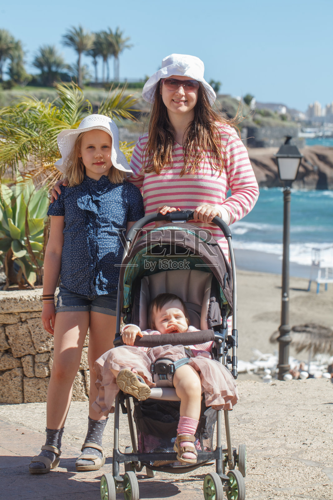 快乐的家庭。母亲和两个女儿在海边散步，享受夏日假期。照片摄影图片