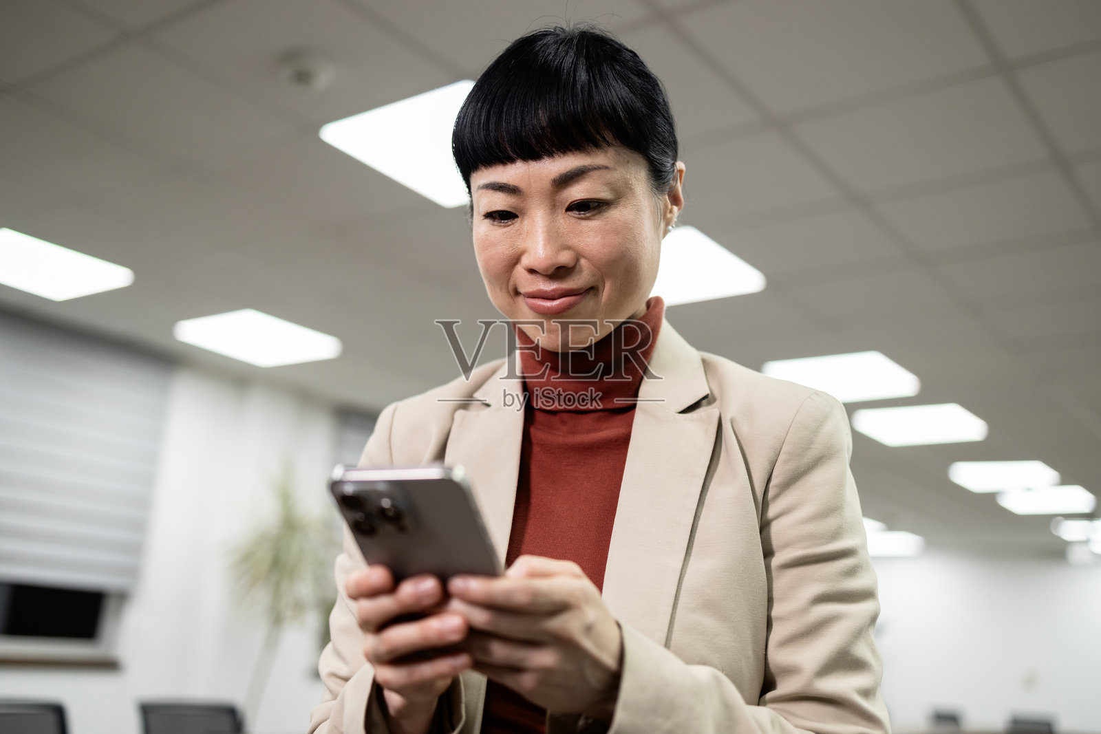 成功的日本女商人在工作时使用智能手机。照片摄影图片