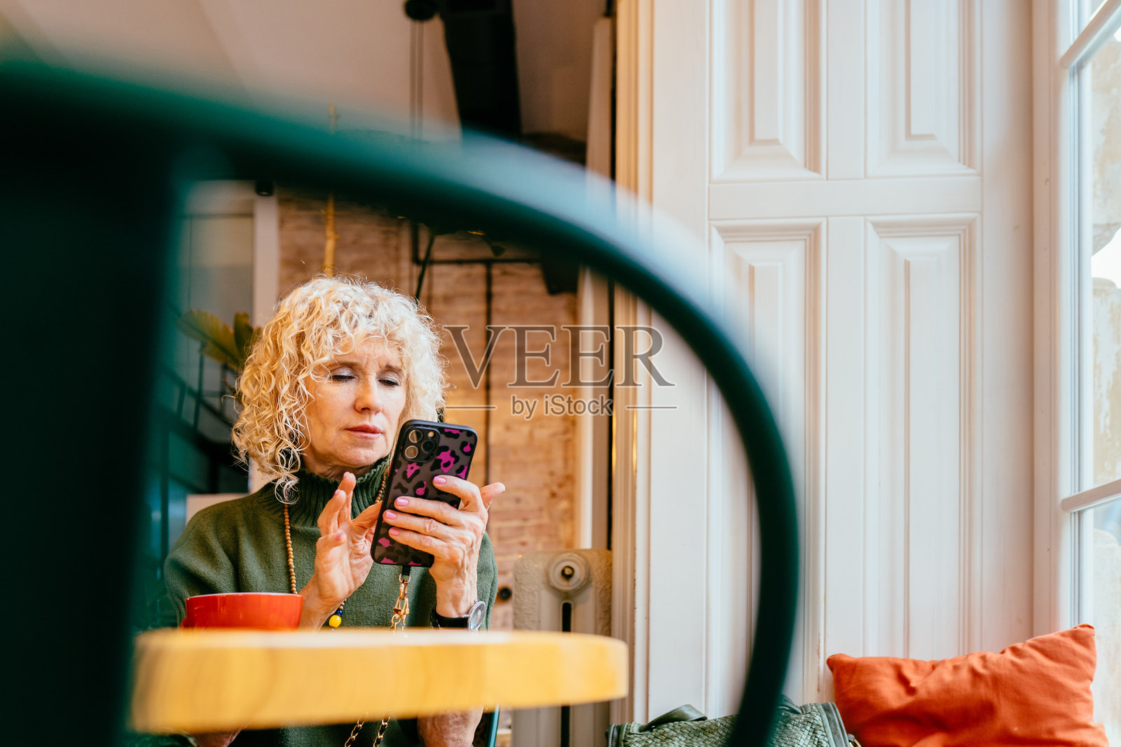 在公共咖啡馆中使用手机的老年女性照片摄影图片