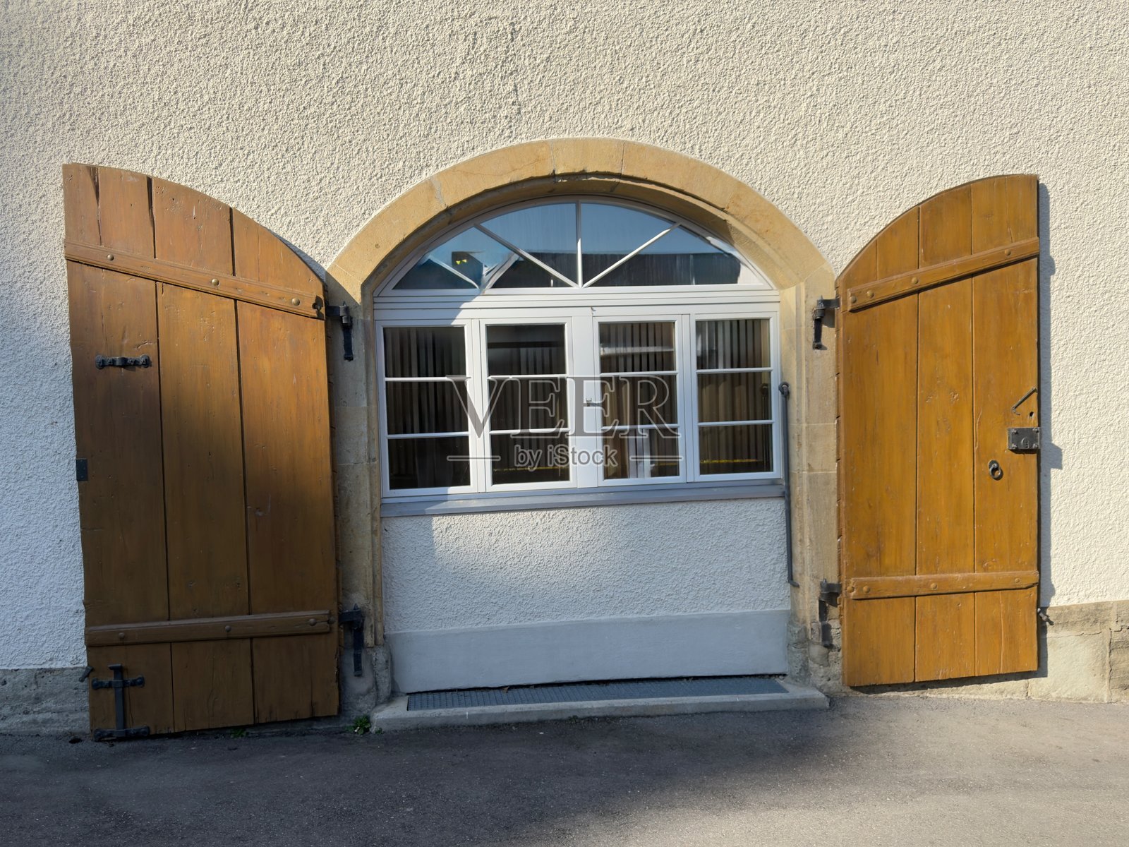 一面白色墙壁上有一个石框拱形窗户。照片摄影图片