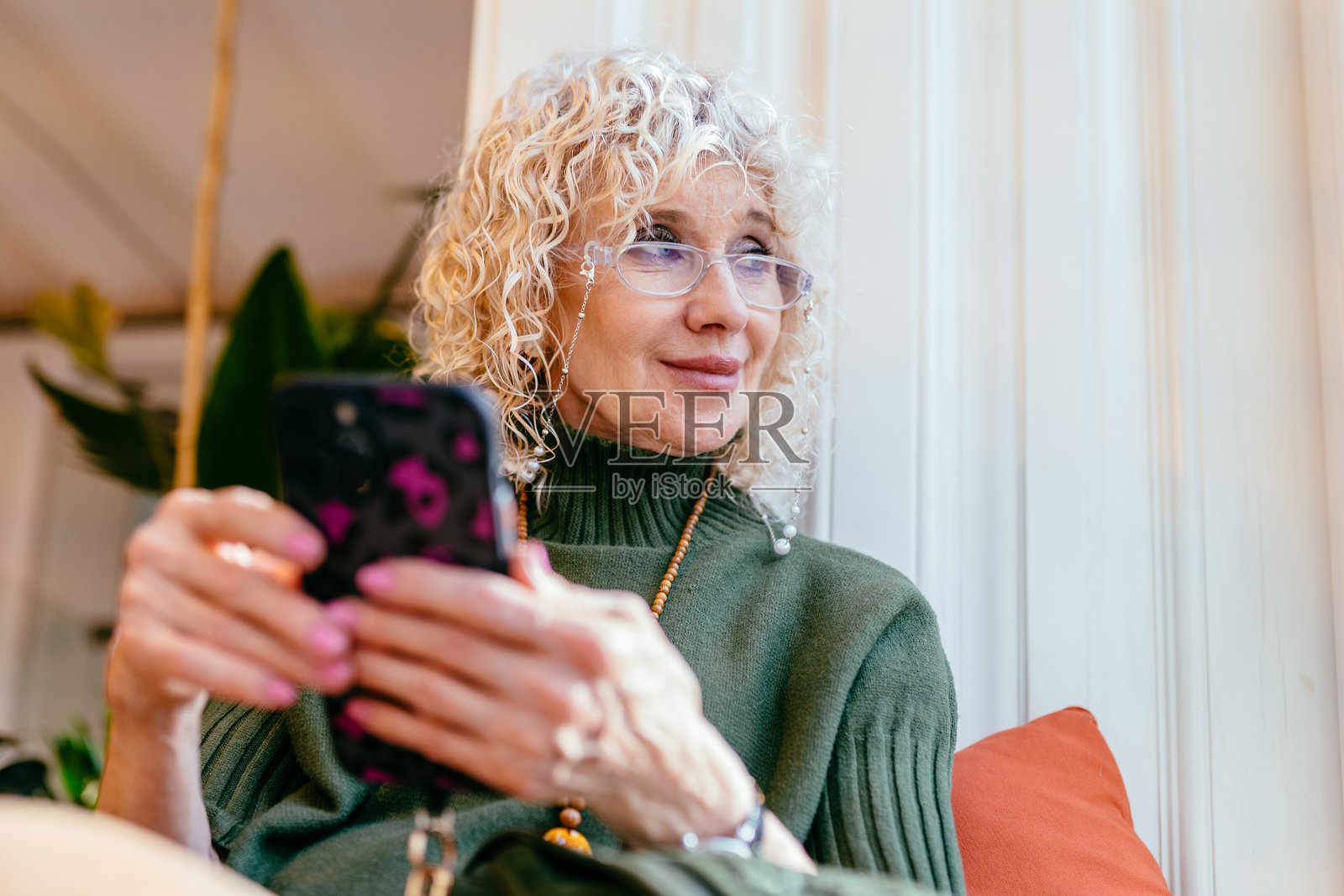 微笑着使用智能手机的老年女性照片摄影图片