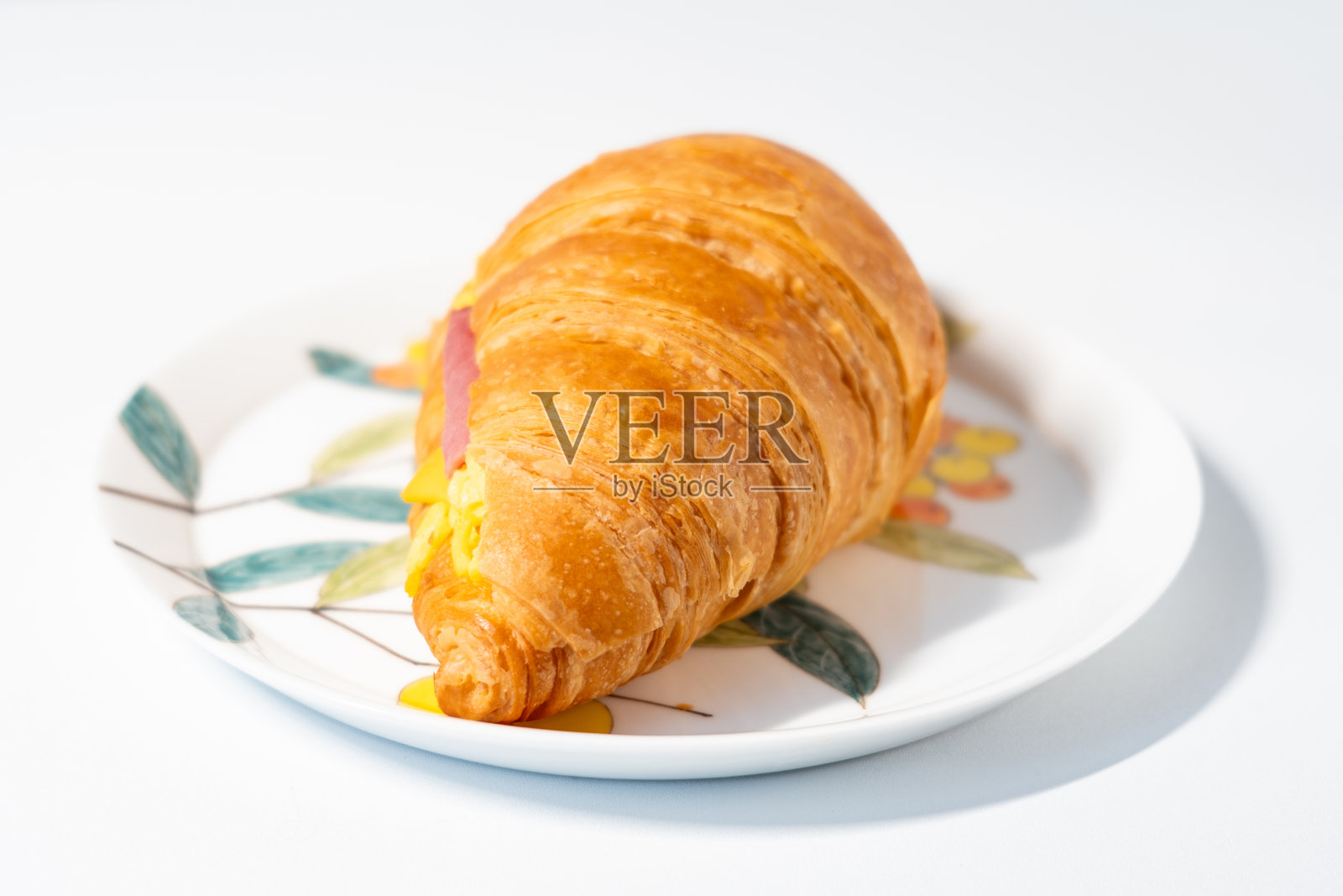 一块牛肉奶酪可颂放在中国白色涂漆盘子上，背景为白色照片摄影图片