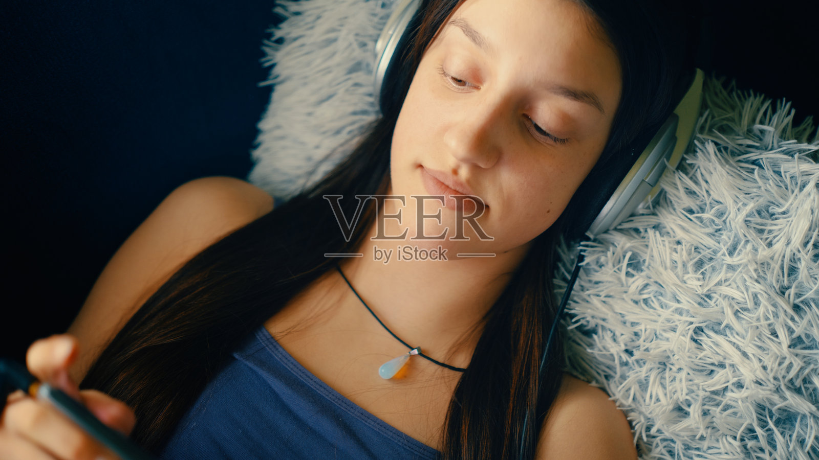 一个青少年女孩在一个安静舒适的空间中放松，完全沉浸在她的手机里。照片摄影图片