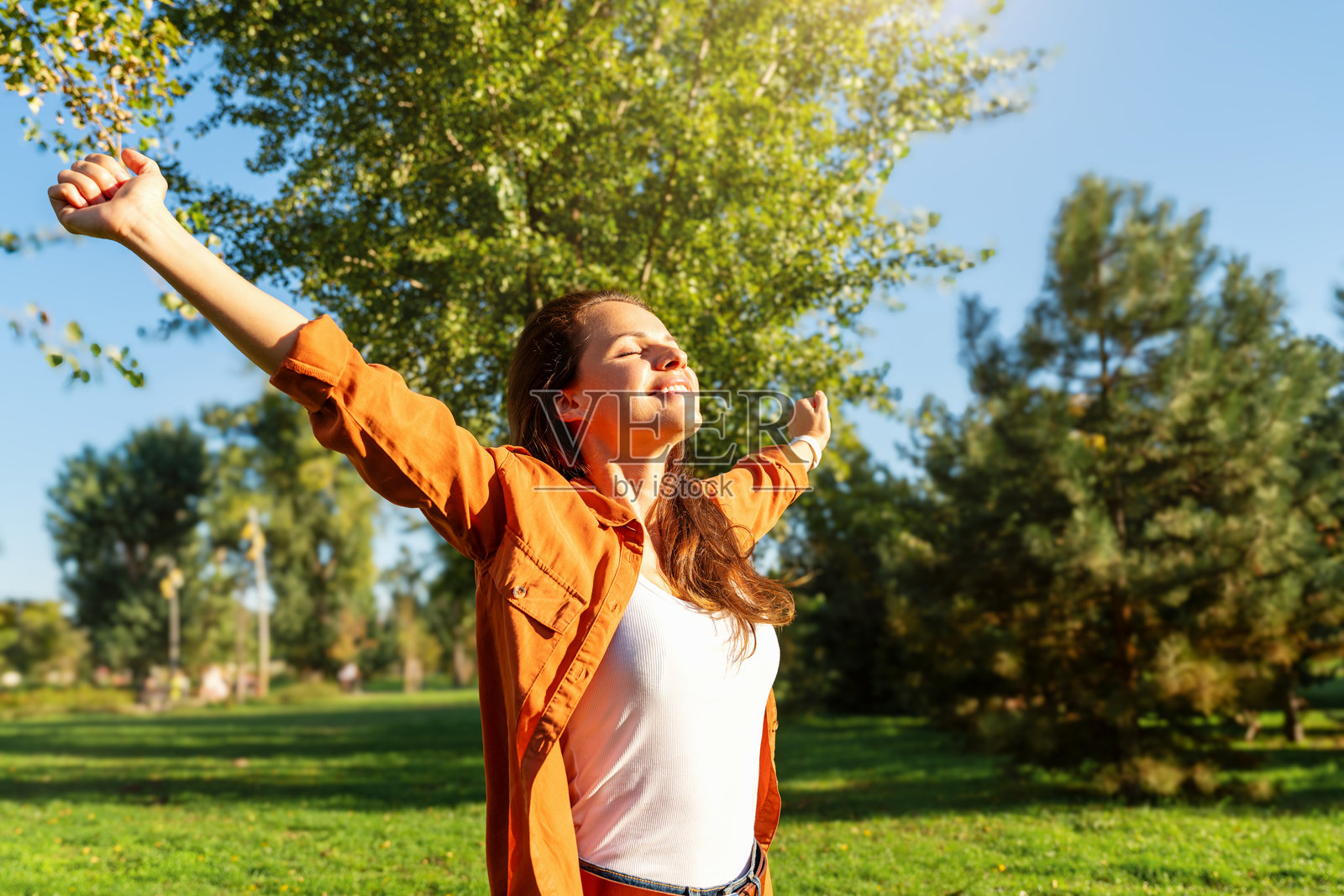 快乐的年轻女性张开双臂欢迎大自然。幸福与健康。照片摄影图片