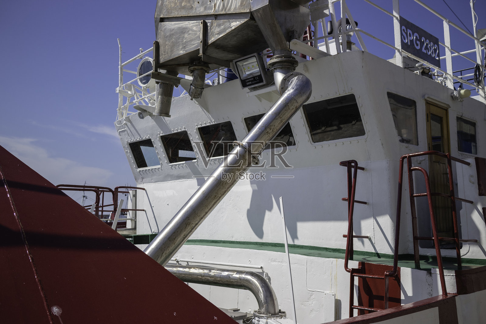 一艘红白相间船体的大船，侧面有一个银色的管道。照片摄影图片
