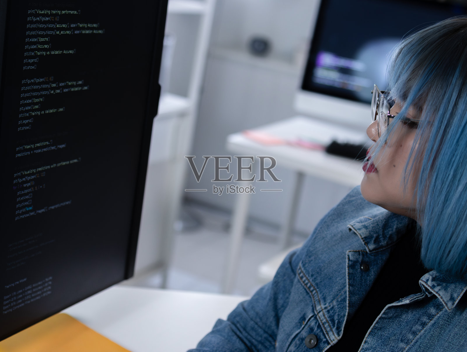 专业的亚洲女性软件开发人员在电脑上编写程序代码，代码行项目反映在脸上。照片摄影图片