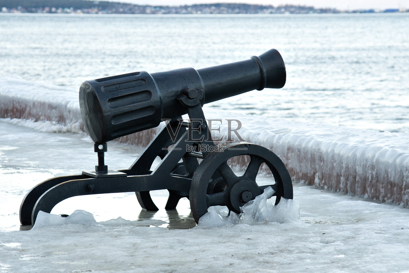一门古老的大炮矗立在雪覆盖的海岸上照片摄影图片