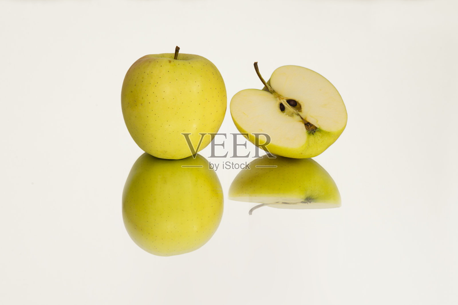 白色镜面背景上的黄色苹果照片摄影图片