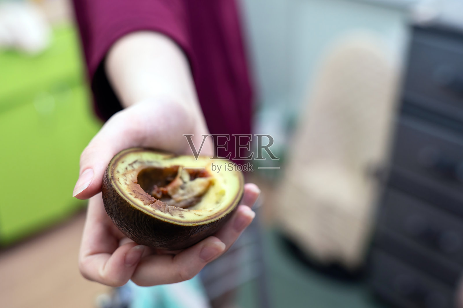 手握半个成熟的鳄梨，展示新鲜健康的食物和自然营养，构图简洁。照片摄影图片