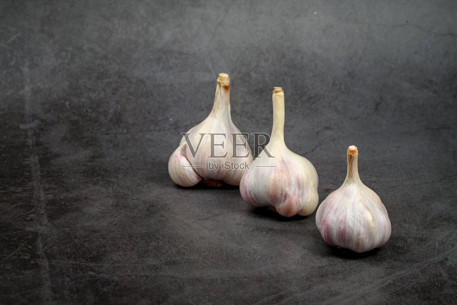 新鲜大蒜头，带有剥落的外皮。紫色大蒜。适合烹饪、健康、食品介绍和营养主题。照片摄影图片