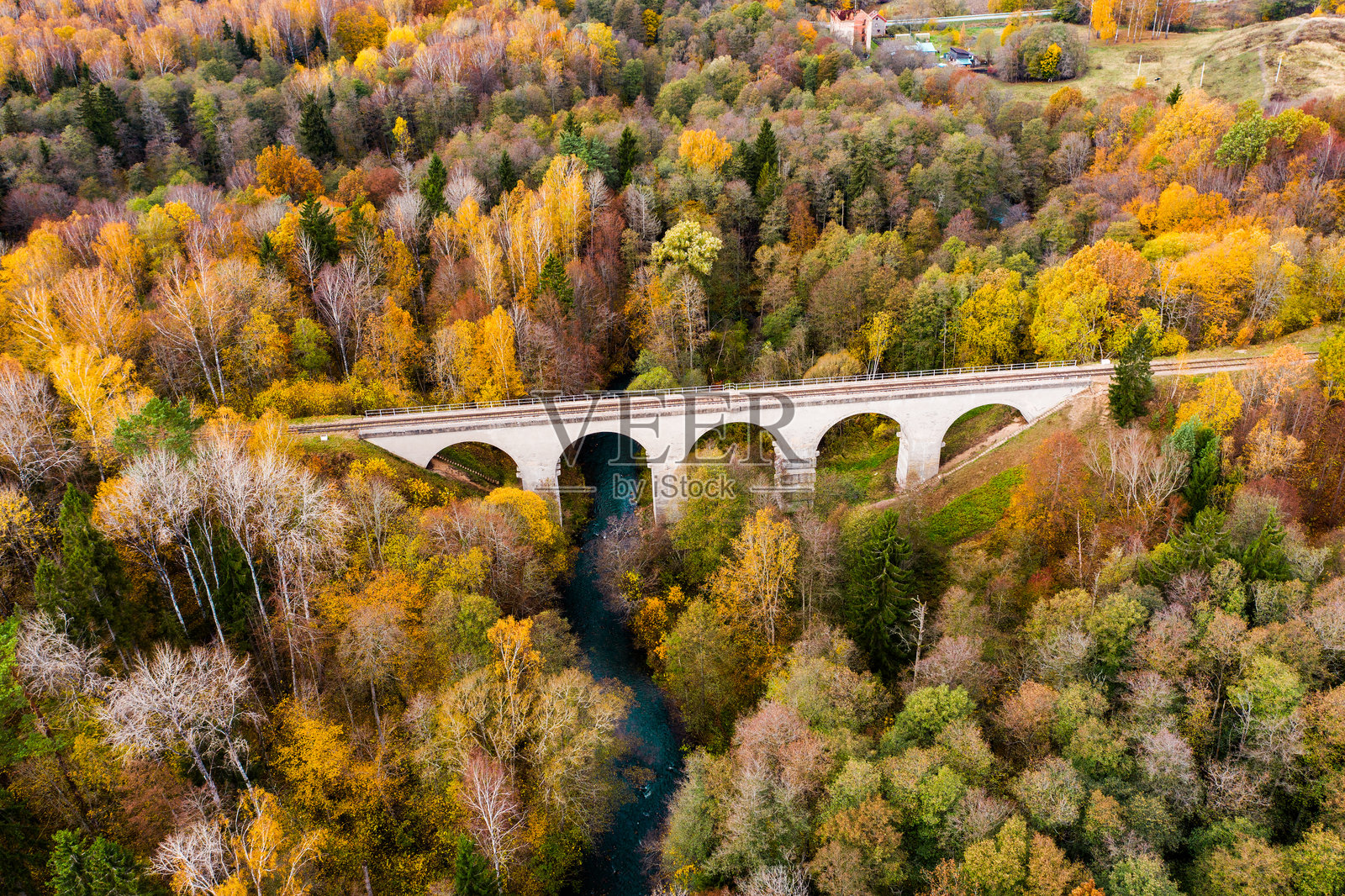 白色拱形铁路桥横跨克拉斯纳亚河，周围是罗明卡森林中的秋季森林照片摄影图片