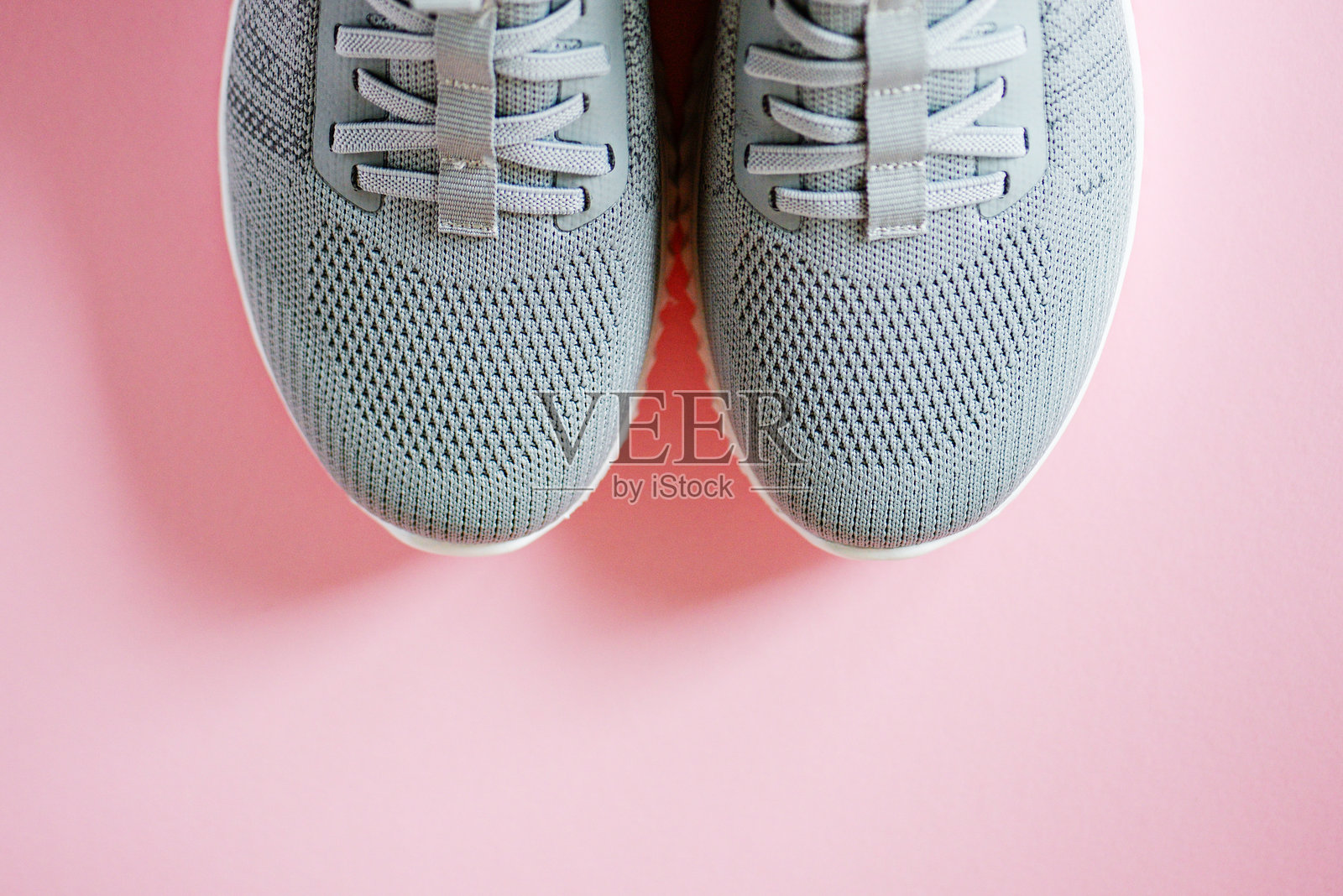 灰色女性运动鞋特写，背景为粉色照片摄影图片