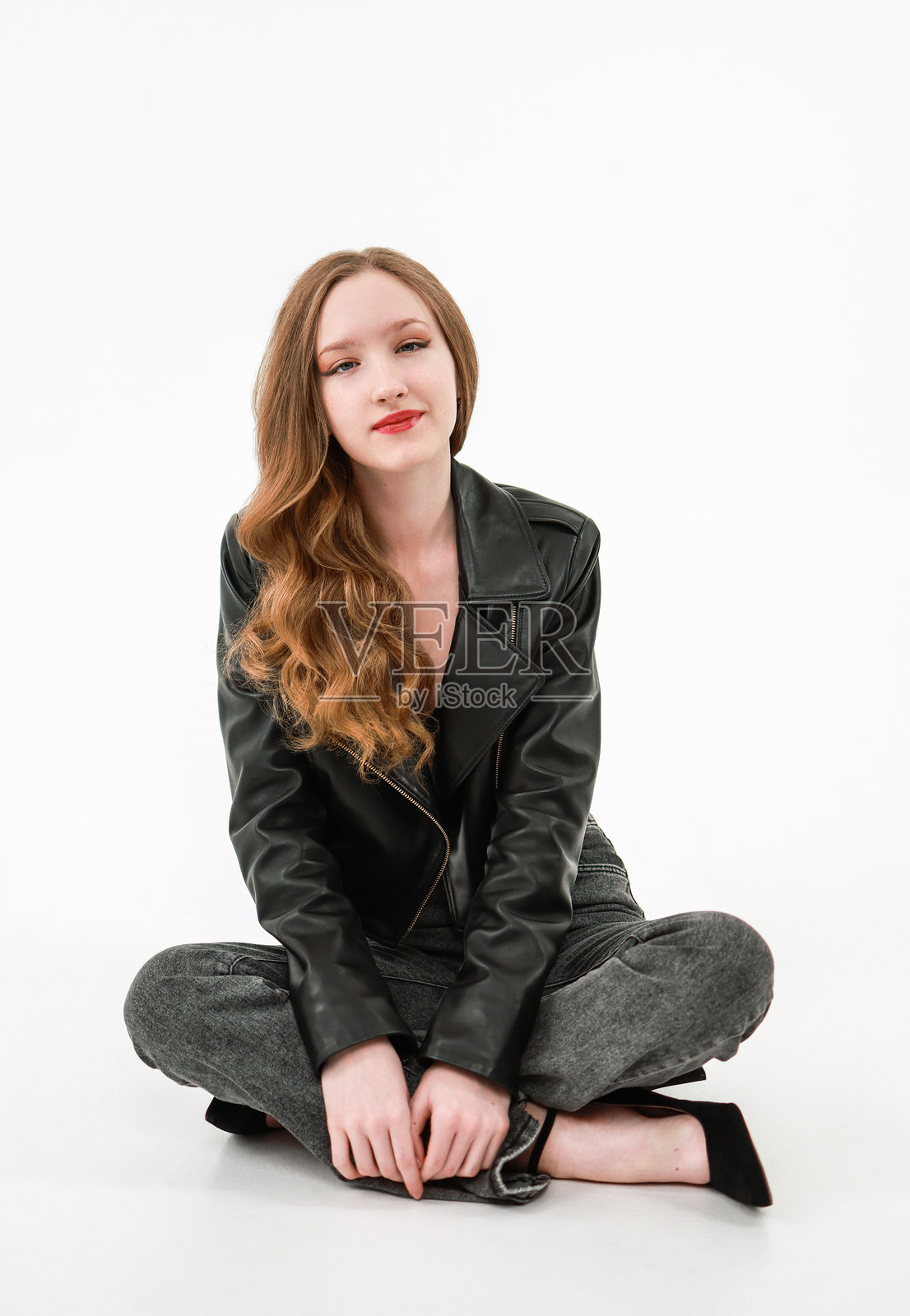 穿着皮夹克和牛仔裤的女孩，背景为白色。照片摄影图片