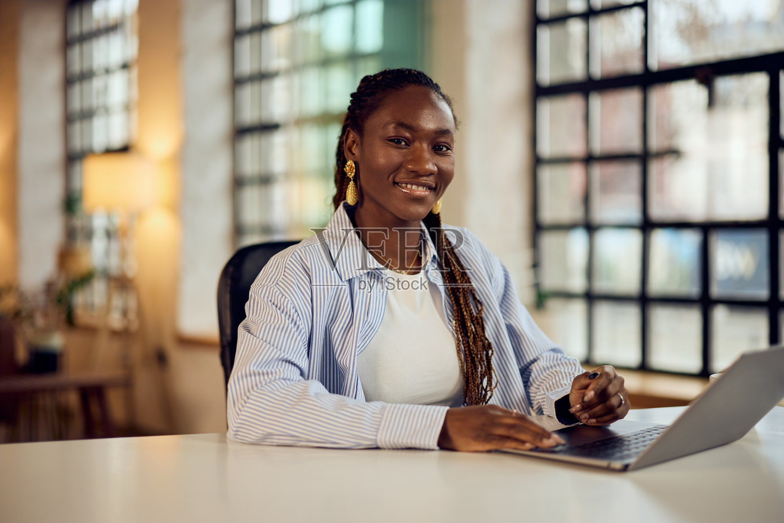微笑的职业女性在现代办公室环境中使用笔记本电脑工作照片摄影图片