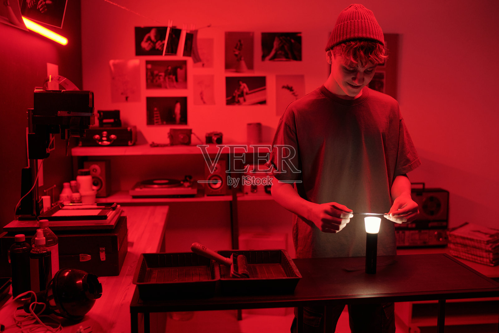 少年男孩在暗房中检查胶卷，正在显影照片。照片摄影图片