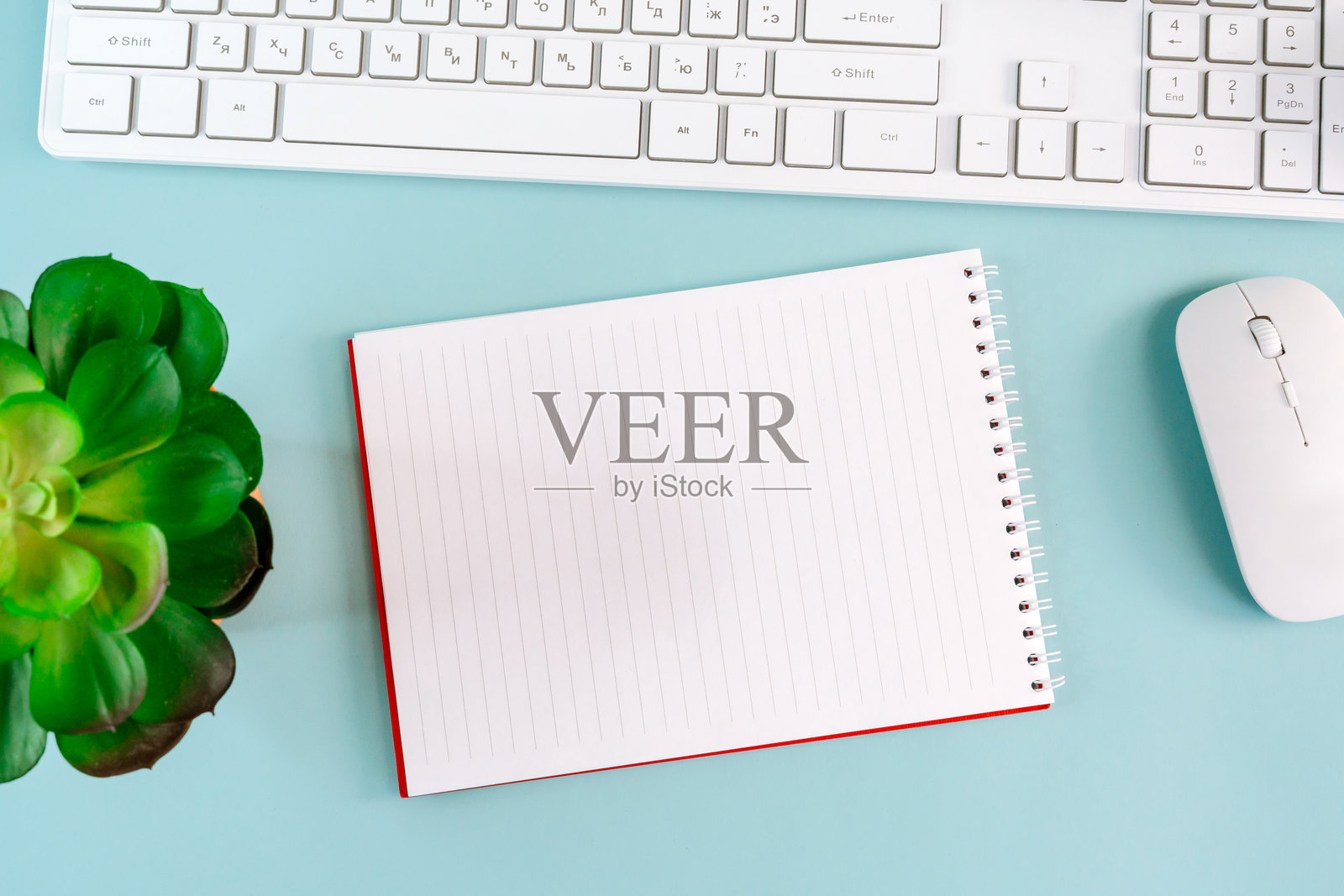 一个笔记本上有文字区域，旁边是一个春季花束，放在蓝色背景的工作场所键盘旁。平铺，样板，俯视，自由职业概念。照片摄影图片