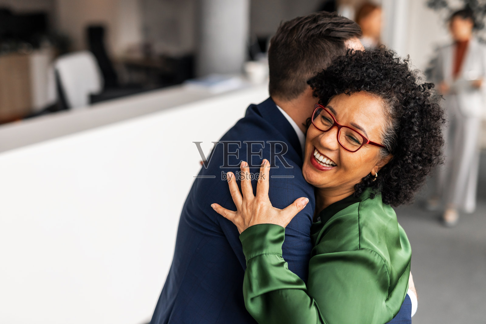 微笑的同事在现代商务办公室环境中拥抱照片摄影图片