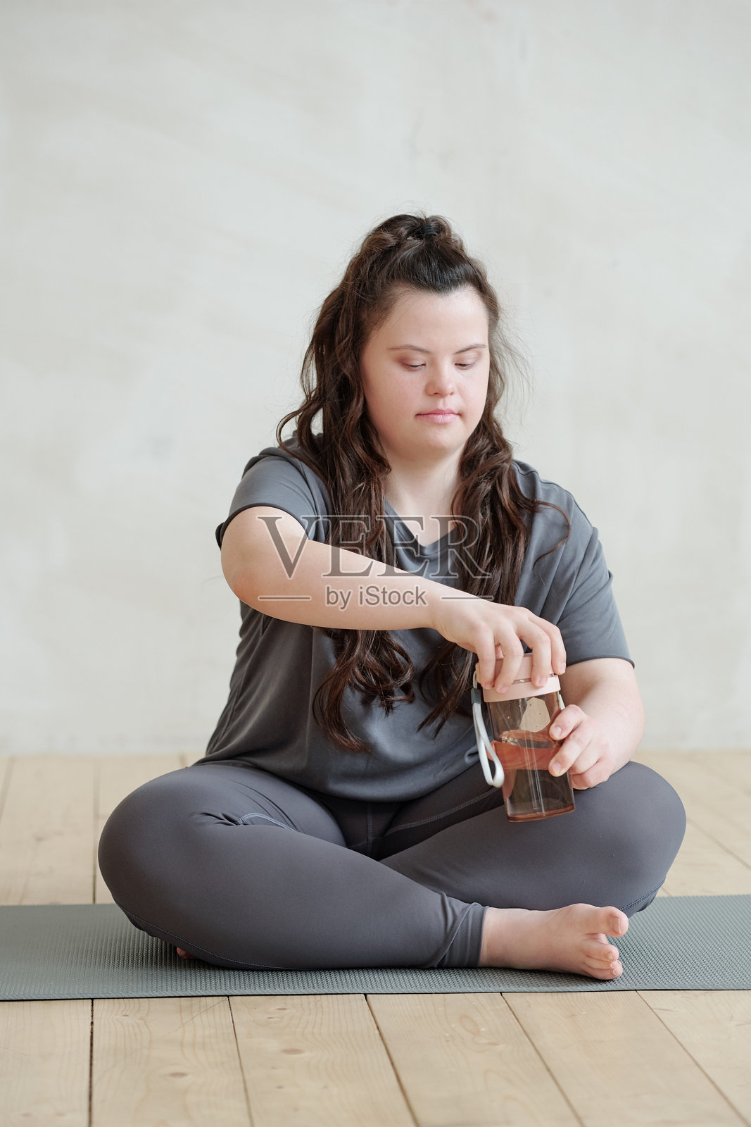 年轻的残疾女性正在打开装有水的塑料杯照片摄影图片