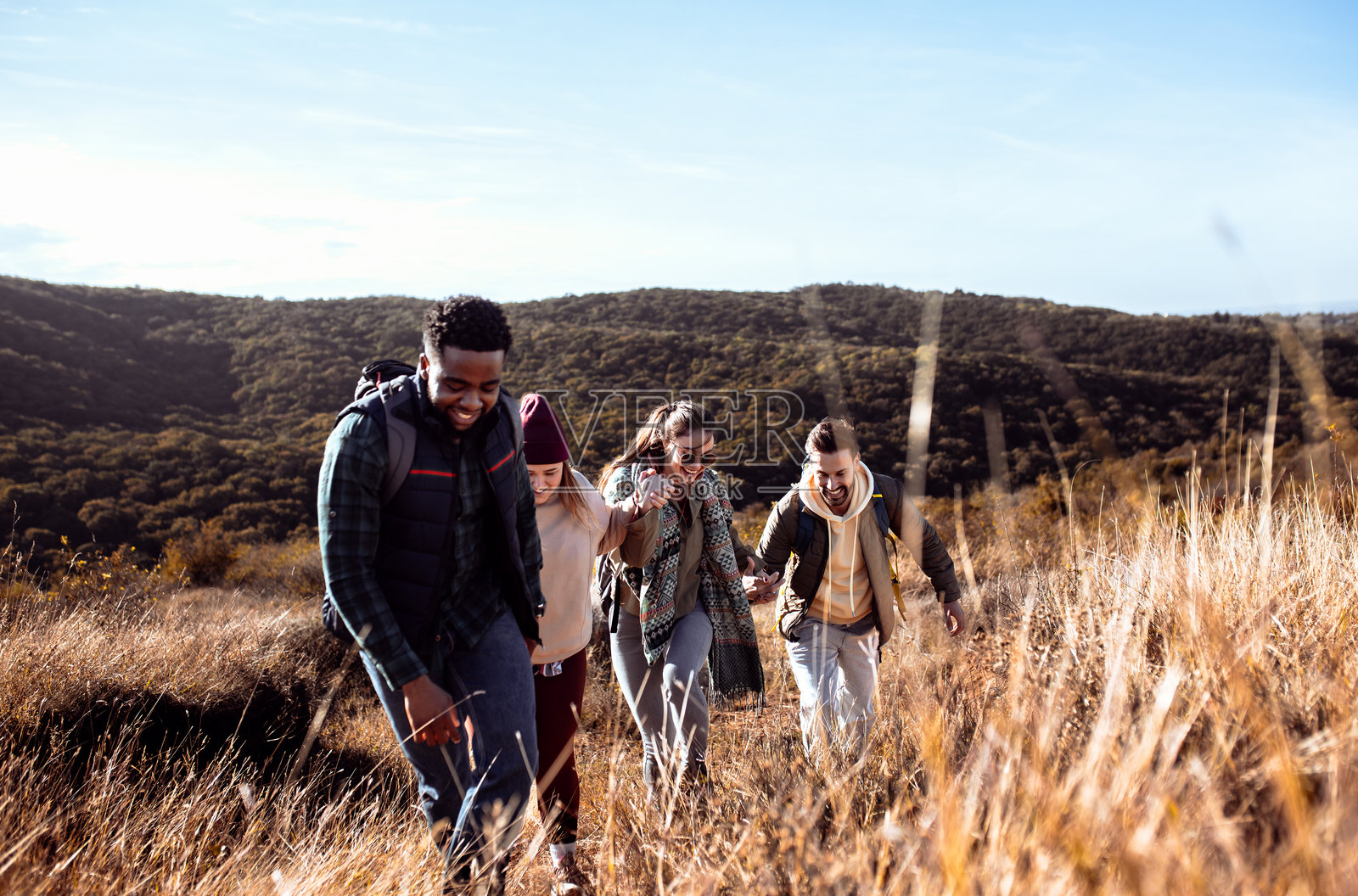 一群微笑的朋友在山上徒步旅行时手牵手，享受快乐时光。照片摄影图片