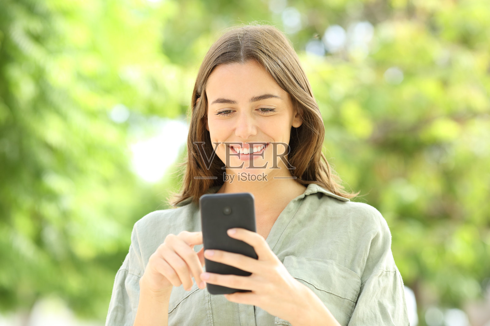 在公园里走路的女性使用手机照片摄影图片