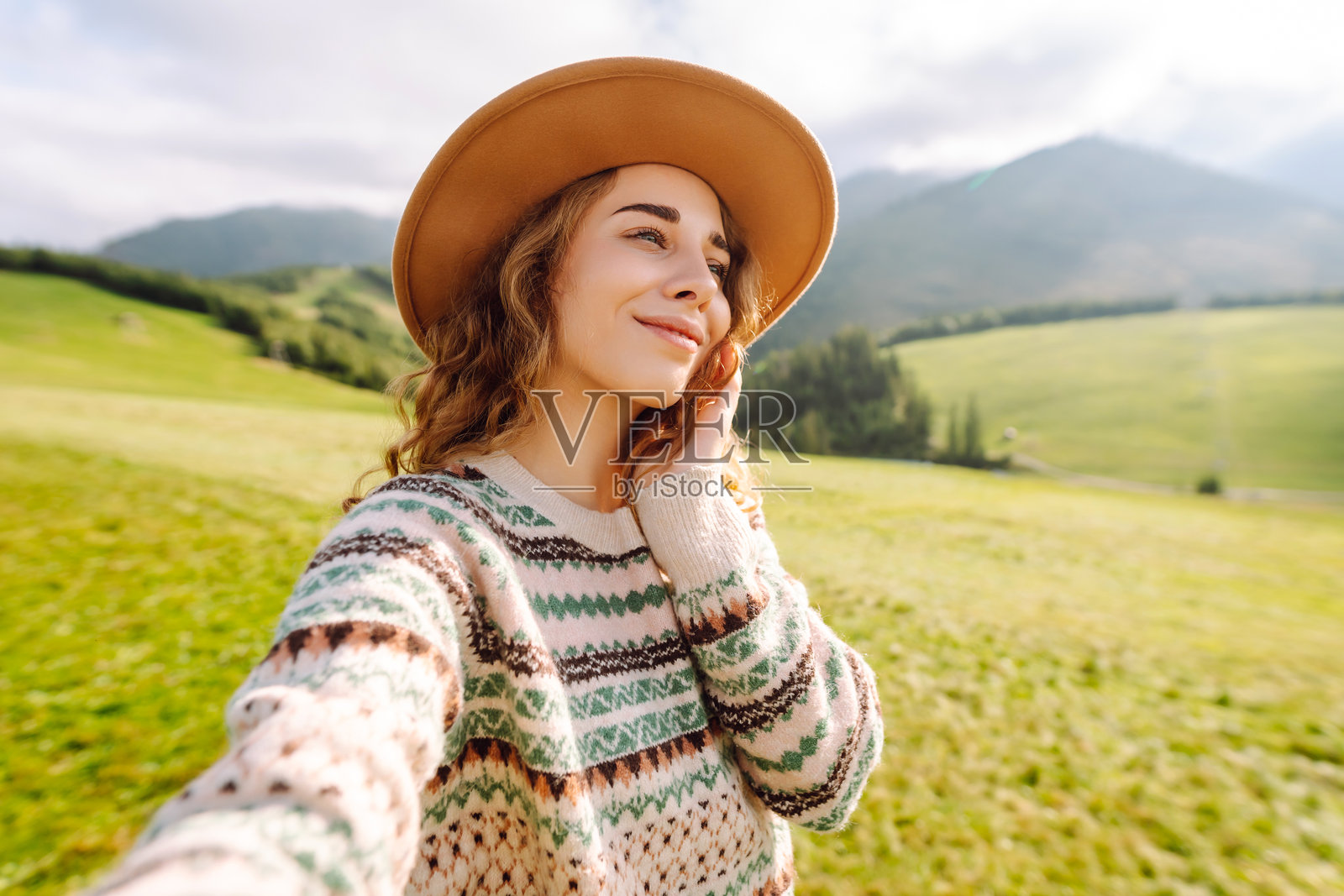 年轻漂亮的女徒步旅行者在山顶拍摄自拍照。照片摄影图片