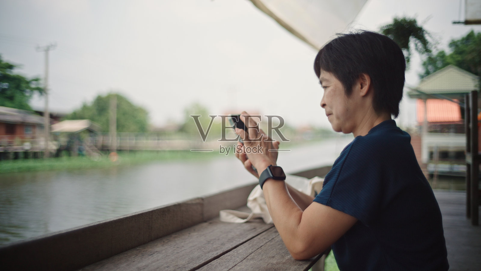 女人在河边放松并拍照。照片摄影图片