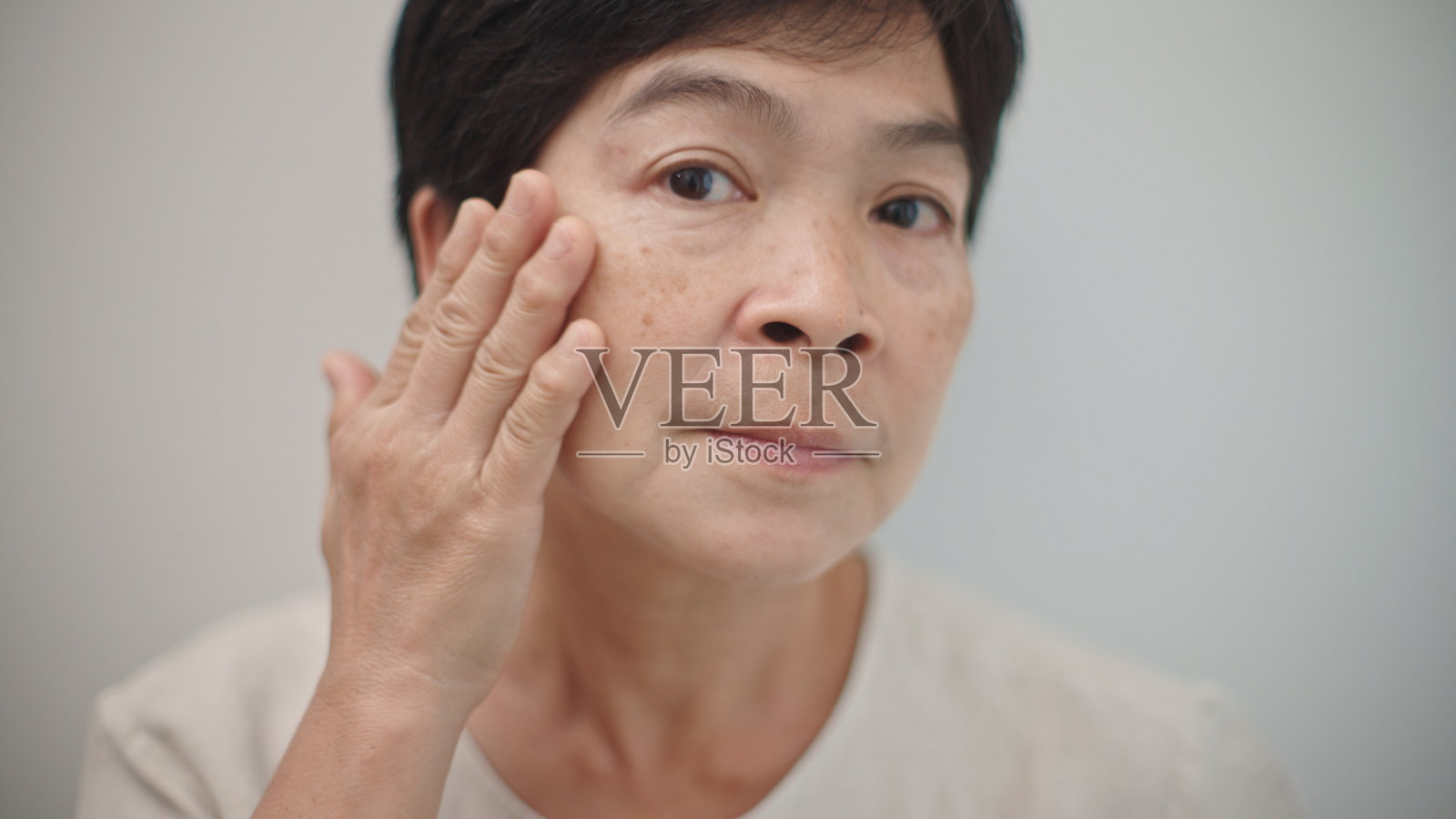 成熟的女性在观察她的皮肤。照片摄影图片