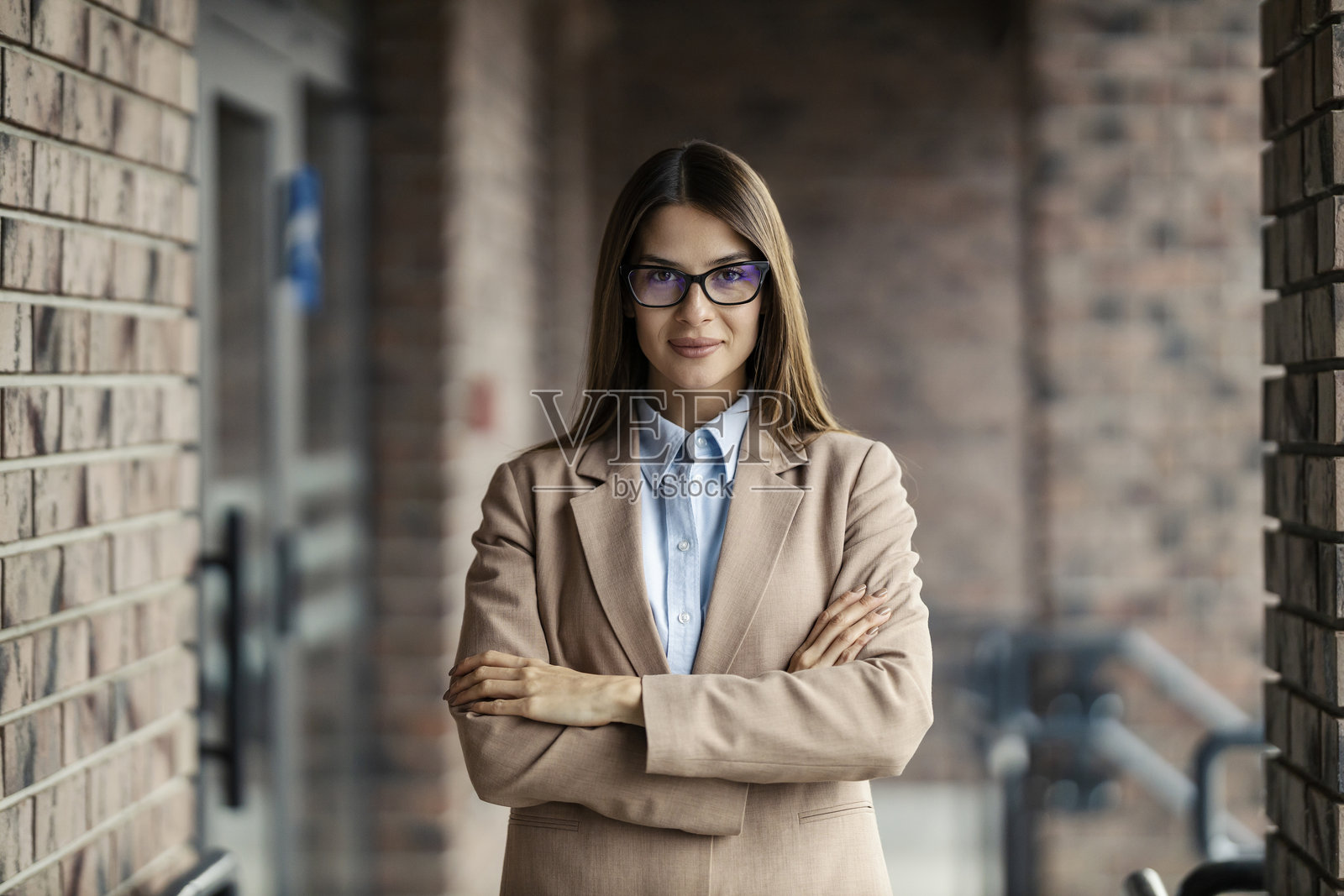 一位成功优雅的女商人站在建筑旁，双臂交叉，注视着镜头。照片摄影图片