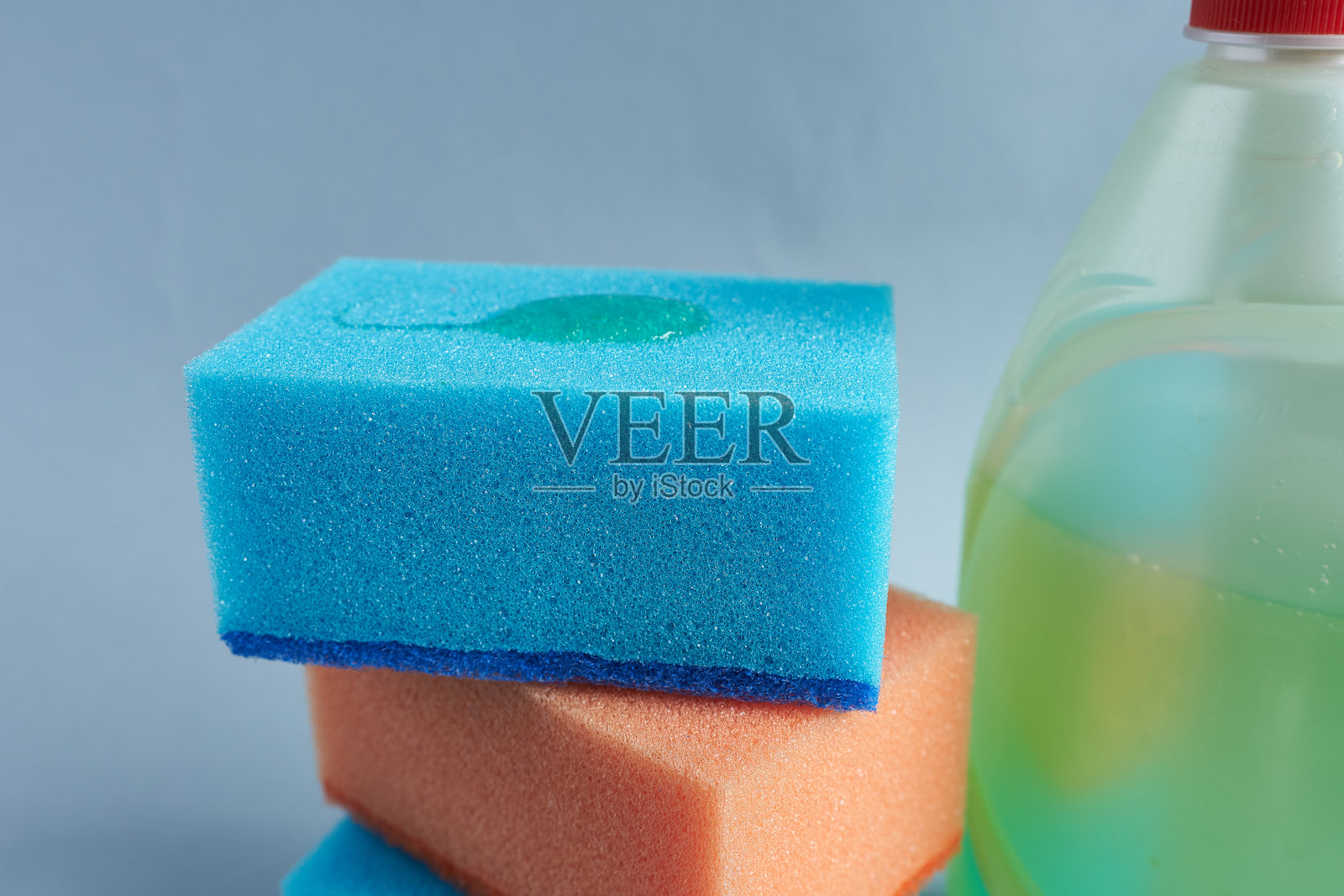 蓝色背景上的海绵和洗涤剂特写照片摄影图片