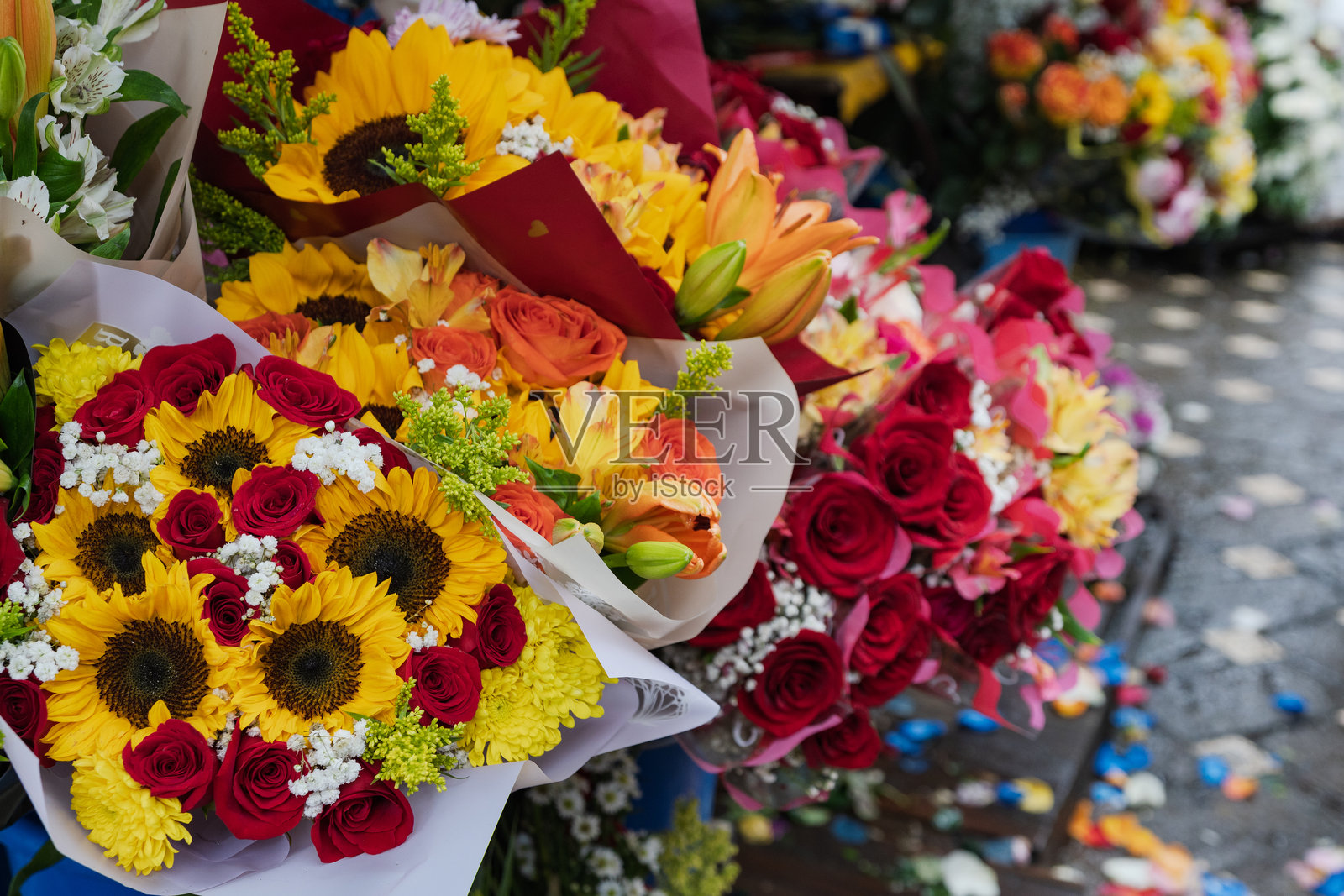 市场上色彩鲜艳的花束，包含向日葵、玫瑰和百合。照片摄影图片