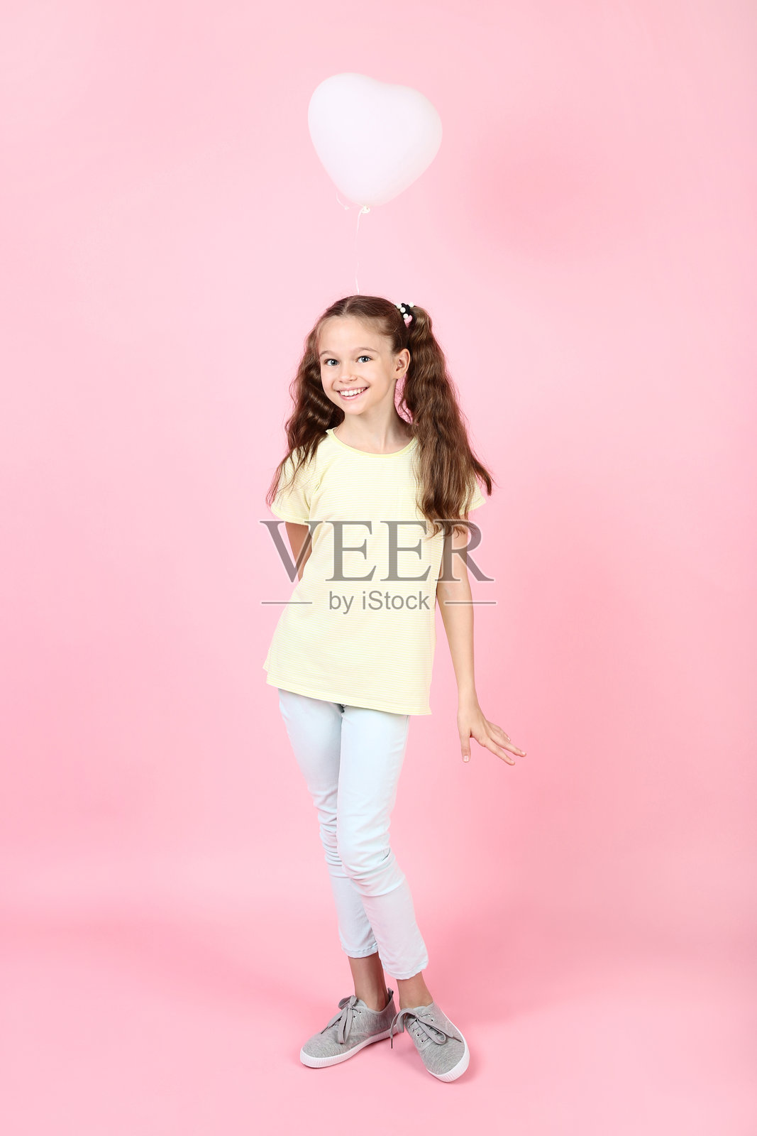 可爱的小女孩手持气球，背景为粉色照片摄影图片