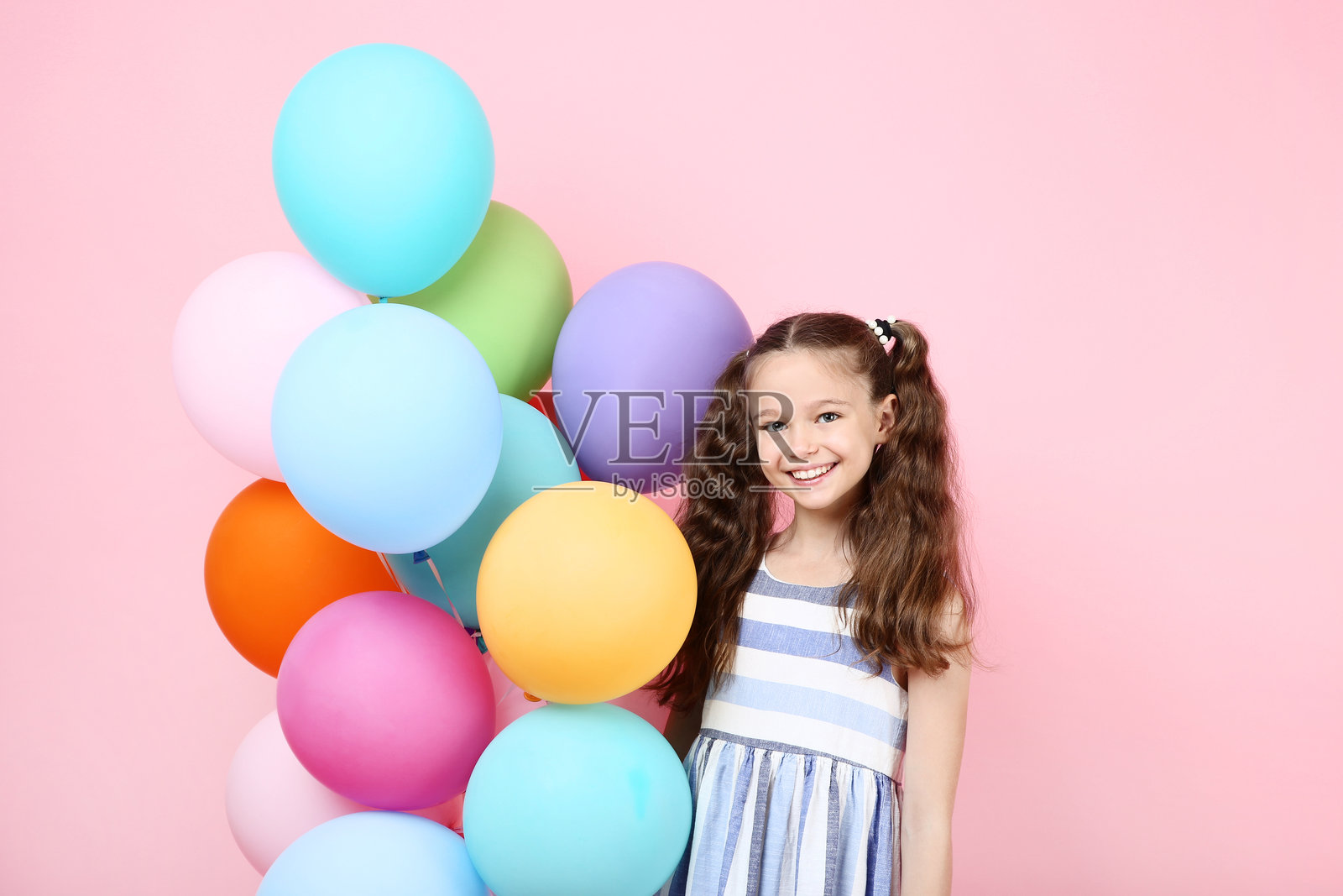 年轻女孩与彩色气球在粉色背景上照片摄影图片