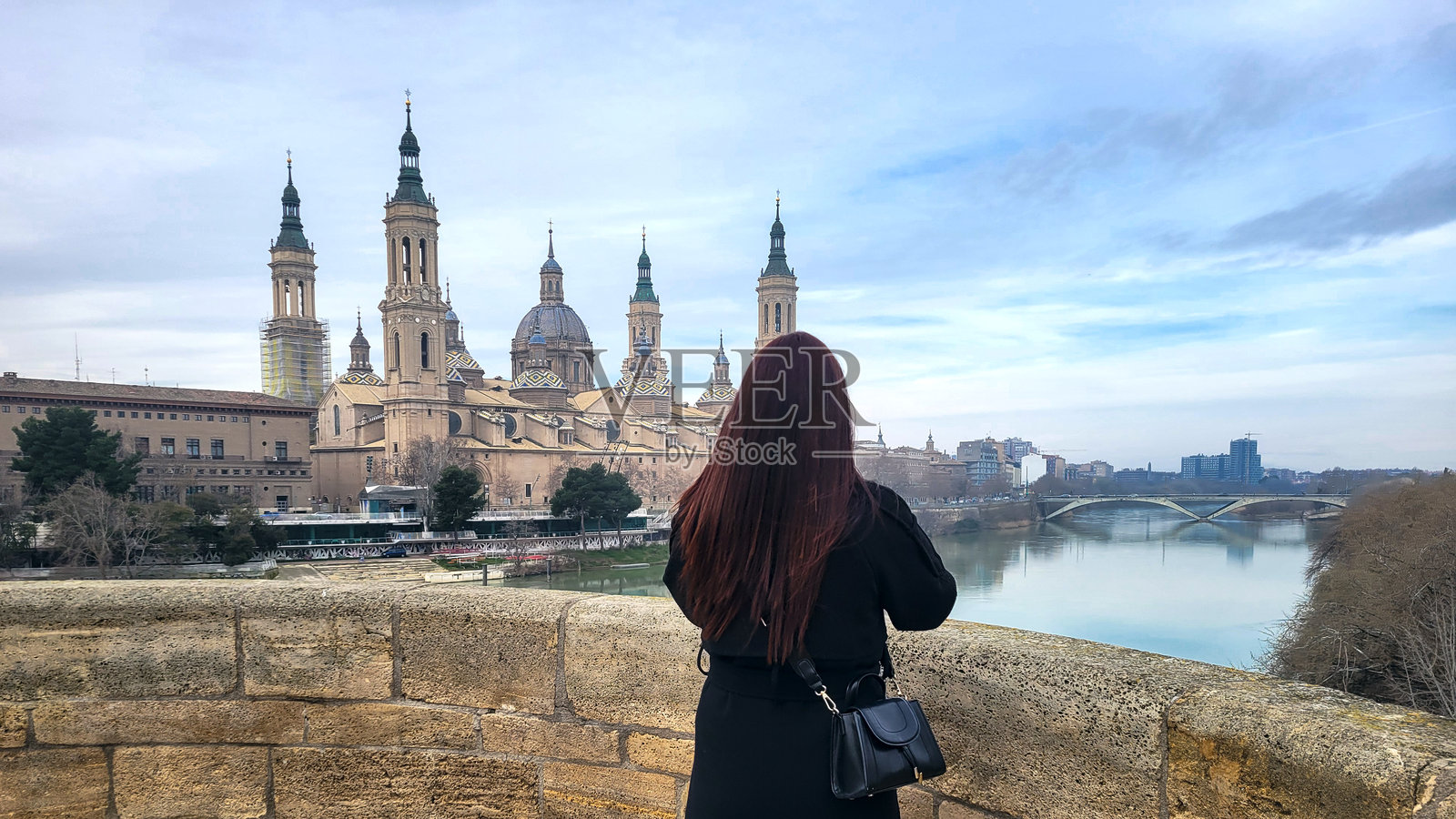 年轻女性在西班牙萨拉戈萨拍摄圣母柱大教堂和埃布罗河的照片照片摄影图片