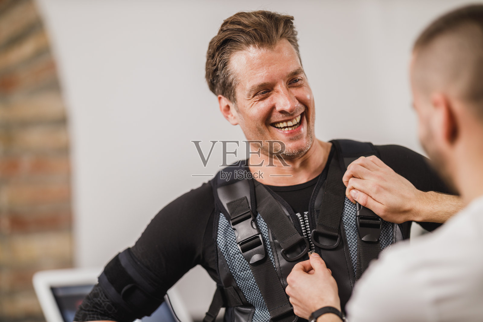 健身教练为一名男性穿上EMS训练服照片摄影图片