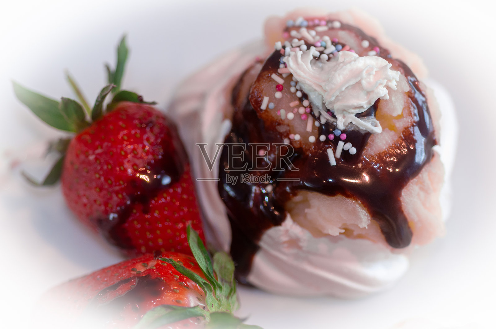 草莓甜点，配有巧克力酱、鲜奶油和糖果撒料。照片摄影图片