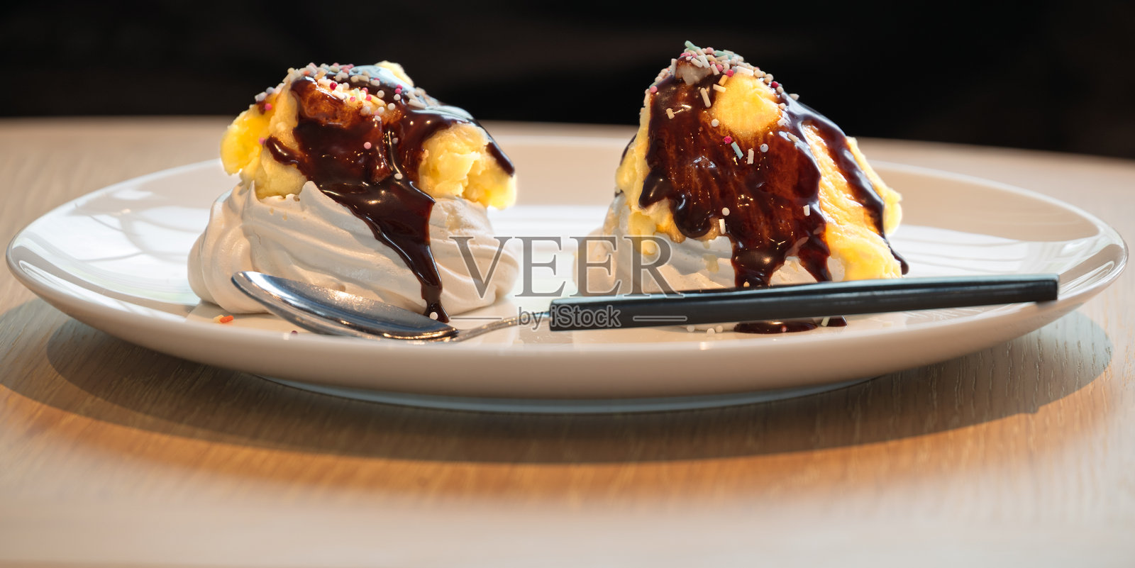 两份淋有巧克力酱和撒上糖屑的帕夫洛娃放在盘子上。照片摄影图片