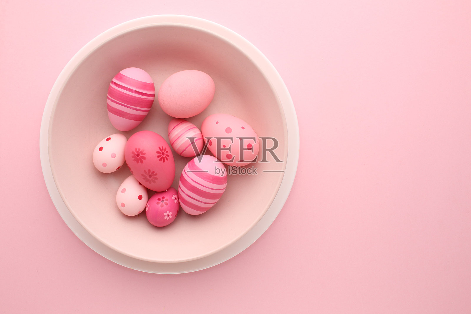 复活节假期。节日装饰。食品装饰。自制饰品。创意多彩的粉色、蓝色、黄色彩蛋排列，带有可爱的兔子和小鸡图案，背景为浅色调。照片摄影图片