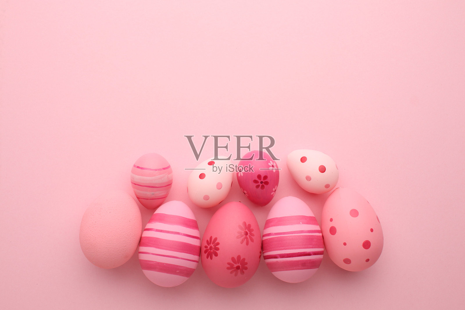 复活节假期。节日装饰。食品装饰。自制饰品。创意多彩的粉色、蓝色、黄色彩蛋排列，带有可爱的兔子和小鸡图案，背景为浅色调。照片摄影图片