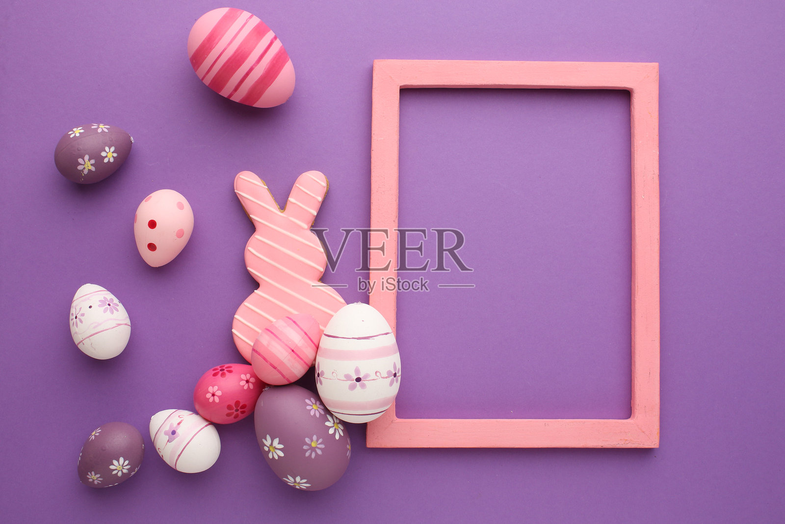 复活节假期。节日组合。食品装饰。自制饰品。创意多彩的粉色、蓝色和黄色彩蛋，带有可爱的兔子和小鸡图案，孤立在浅色粉彩背景上。照片摄影图片