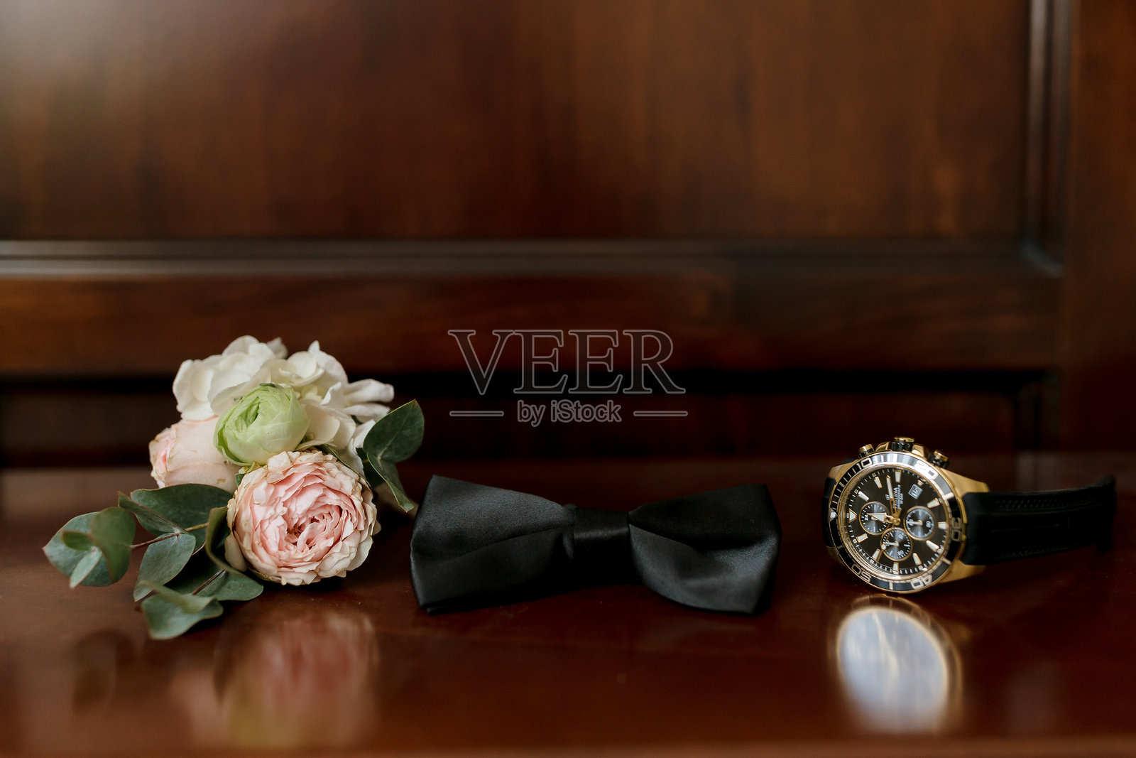 一只手表和一条黑色领结放在桌子上照片摄影图片