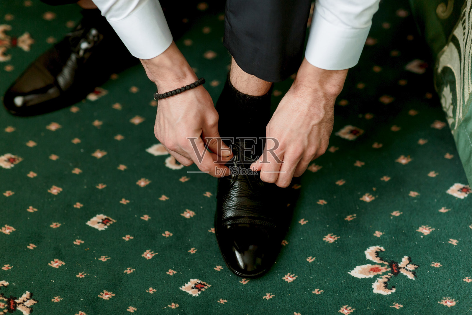 一个男人正在穿鞋，这幅图传达了一种正式感。照片摄影图片