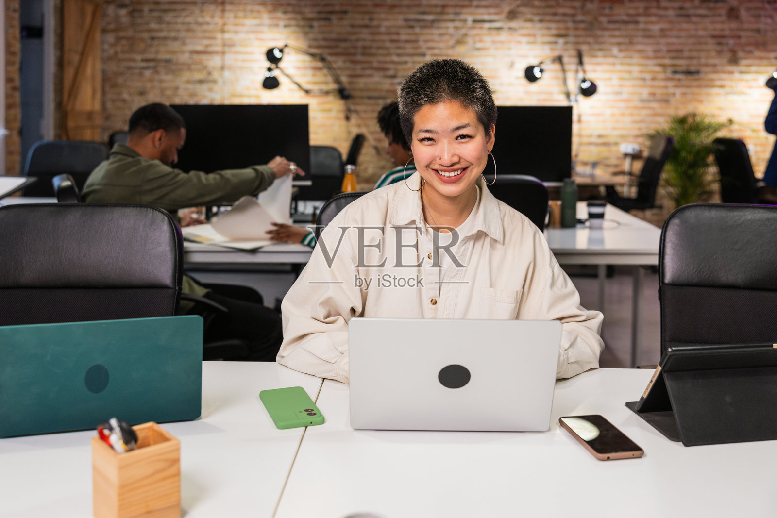 年轻的亚洲女商人在现代办公室里微笑着使用笔记本电脑。照片摄影图片