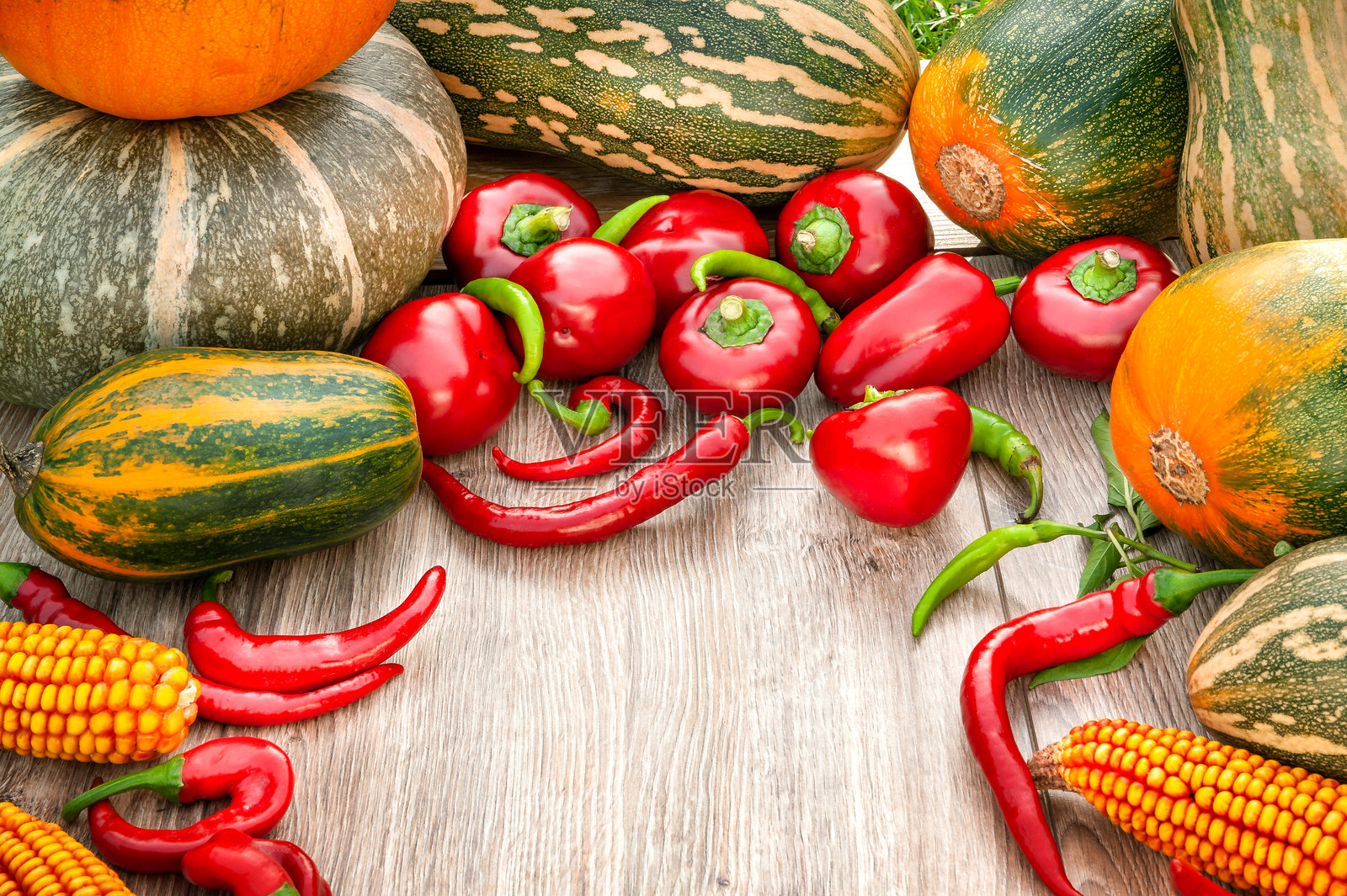 秋季收获的蔬菜。南瓜、玉米、红色和绿色辣椒在木质背景上。照片摄影图片