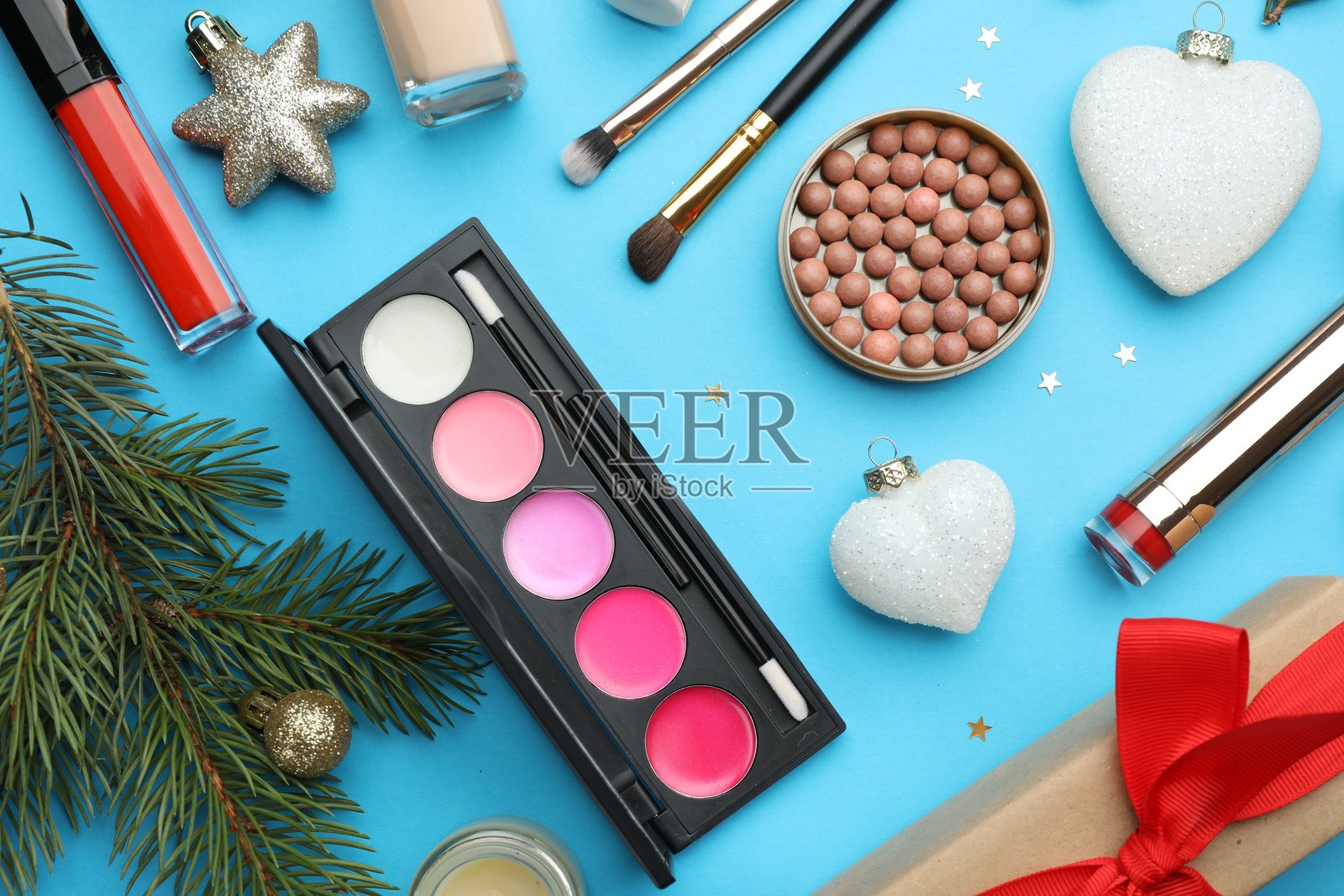 平铺构图，包含化妆品和圣诞装饰，背景为浅蓝色照片摄影图片
