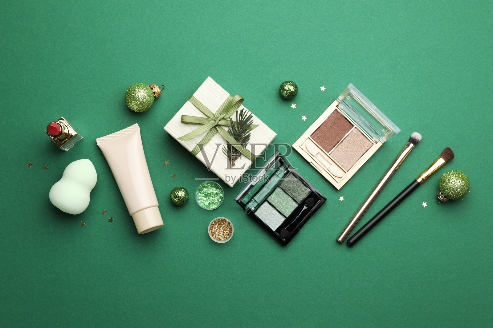 绿色背景上的化妆品和平面圣诞装饰的组合布局照片摄影图片
