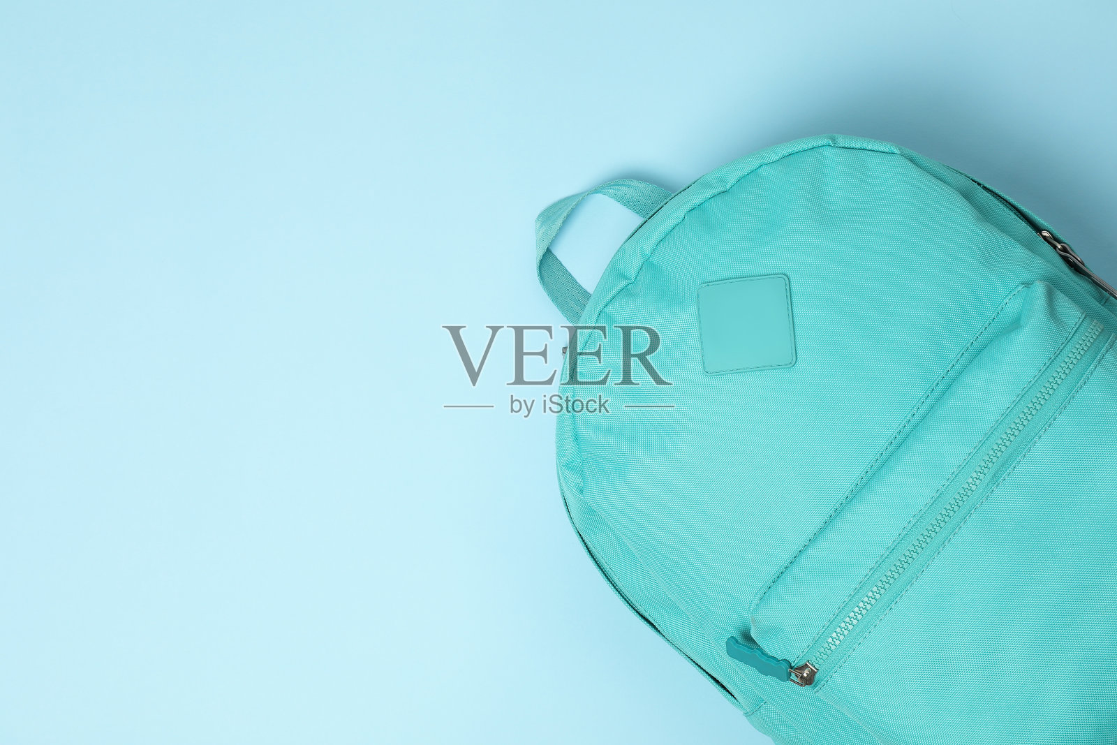 一个明亮的背包在浅蓝色背景上，俯视图。留有文字空间照片摄影图片