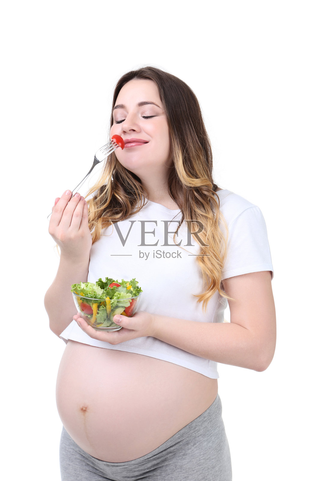 美丽的孕妇手里拿着装有新鲜沙拉的碗，背景为白色。照片摄影图片