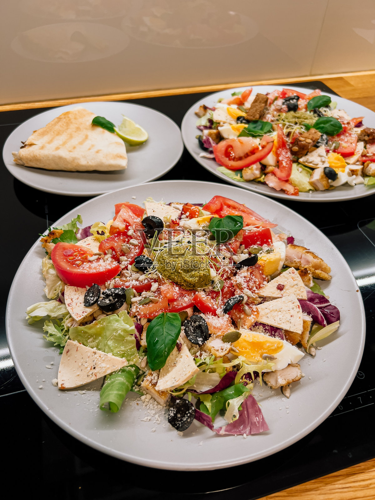 丰盛的自制餐点，搭配新鲜沙拉和温暖的皮塔饼，精心准备的舒适家庭午餐。健康的沙拉和自制配菜在轻松的家庭环境中呈现，简单而美味。照片摄影图片