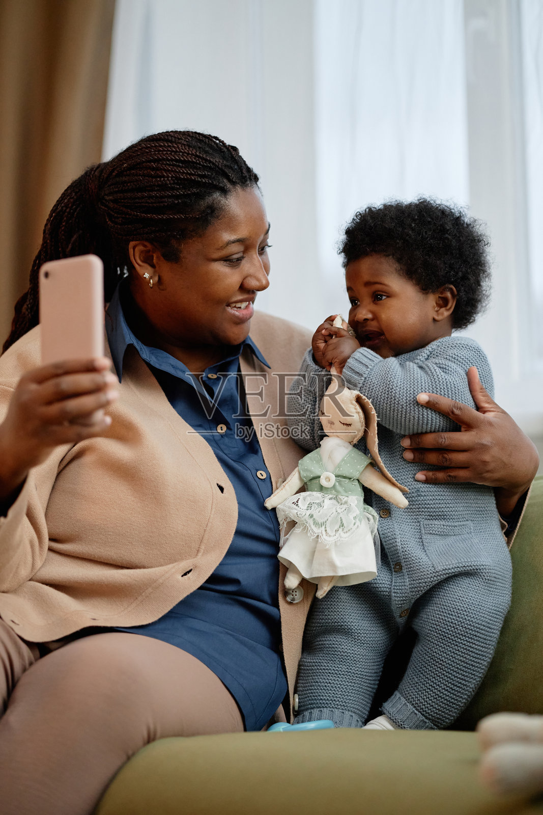 快乐的黑人母亲在家沙发上与手握玩具的小女儿自拍照片摄影图片